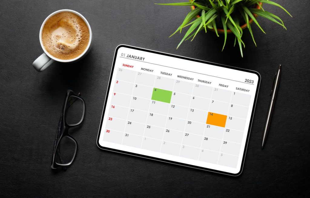 Tablet with calendar app, coffee cup and office supplies